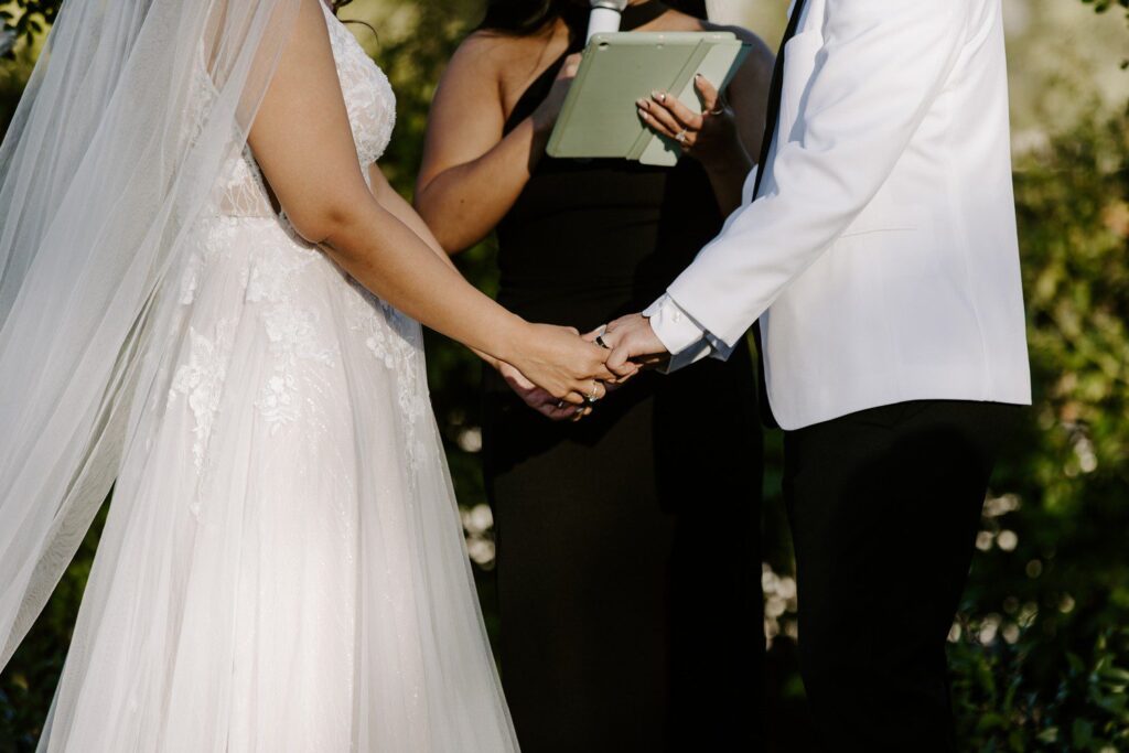 Bride and groom holding hands during wedding ceremony. 