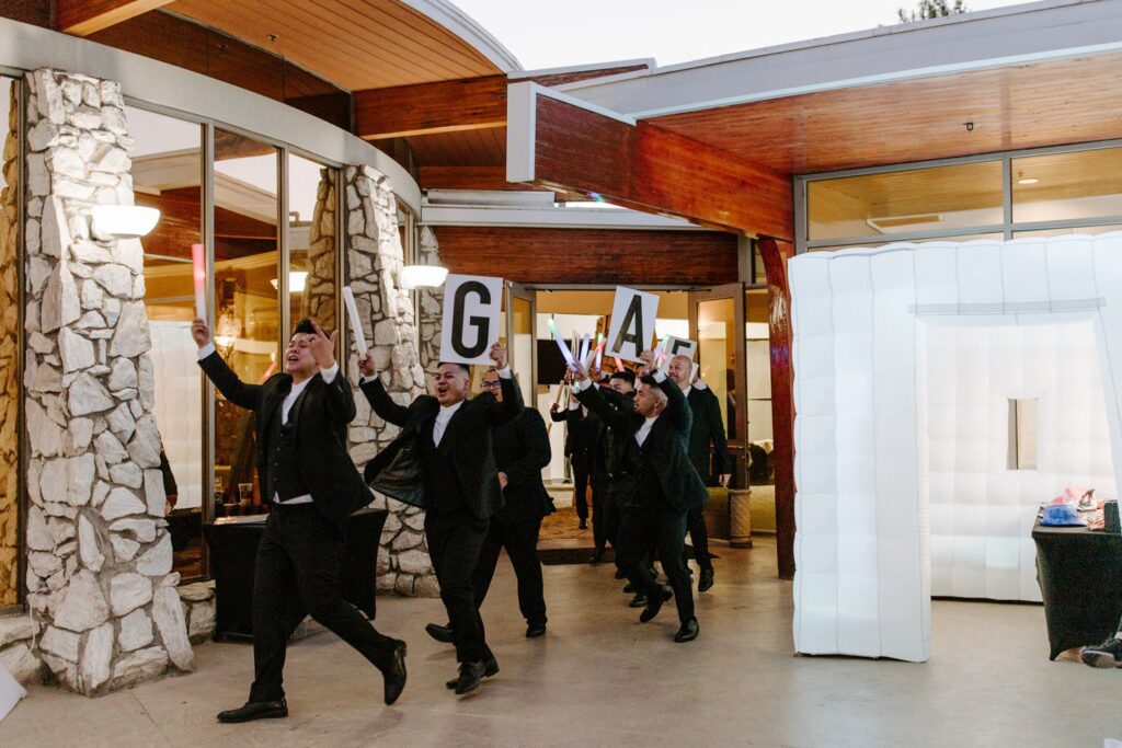 Wedding reception entrance with groomsmen holding signs. 