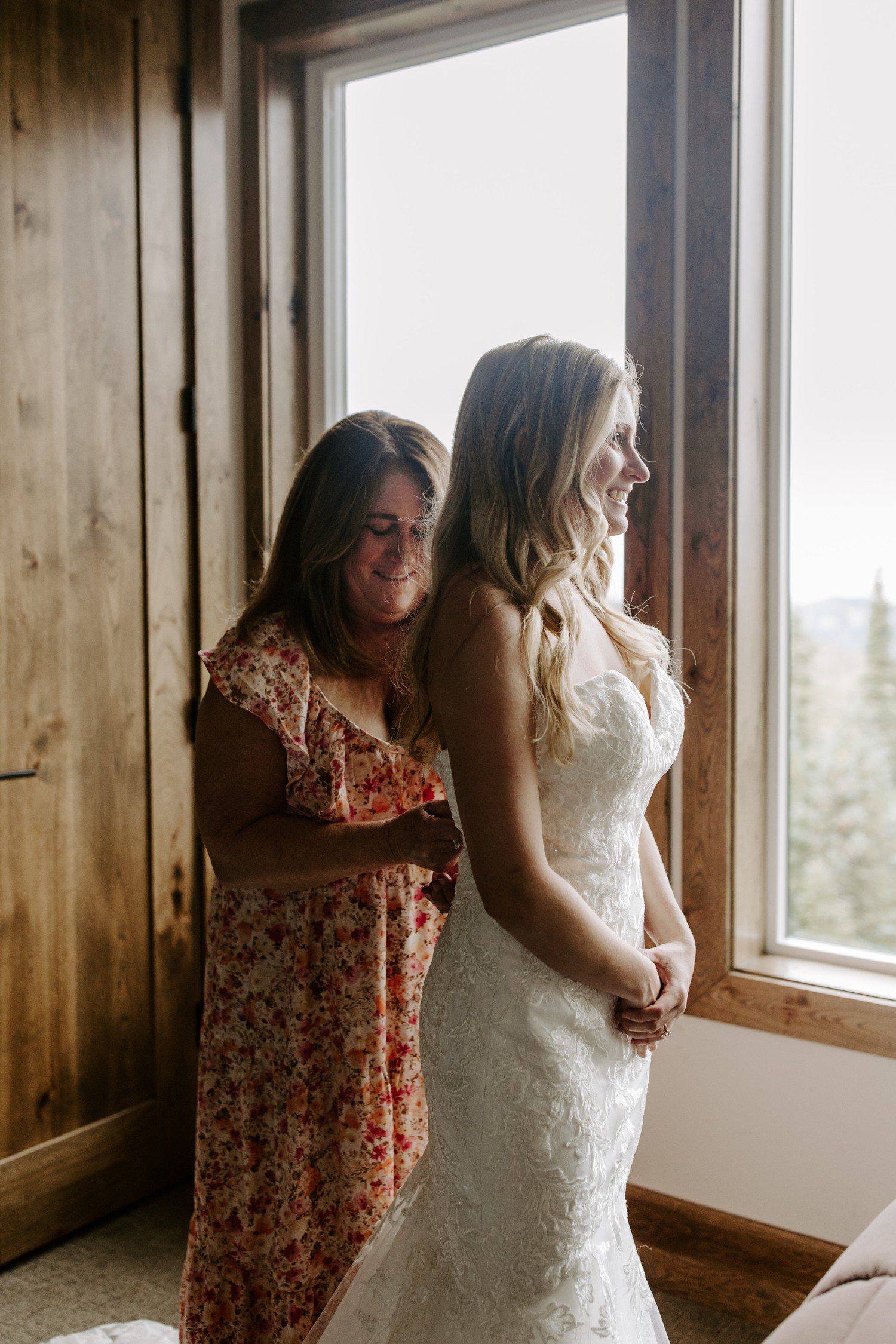 Mom zipping up bride in dress in airbnb in Utah.