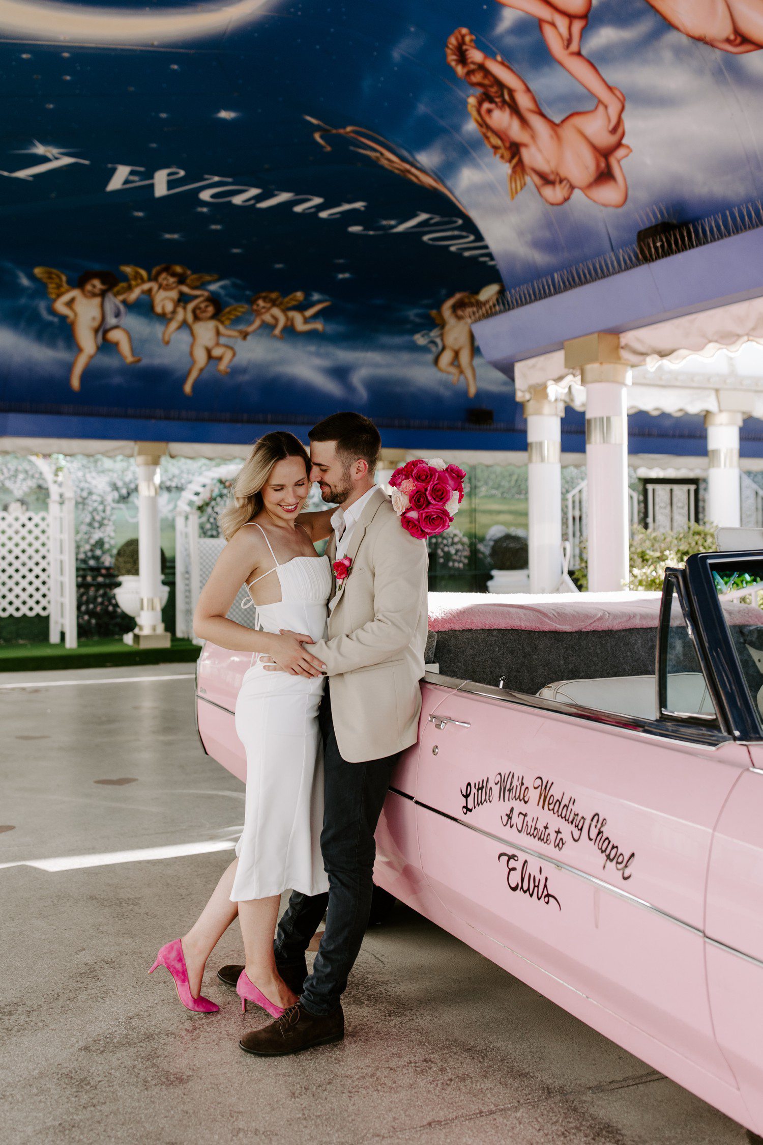 Couple standing by pink Cadillac at A Little White Chapel.