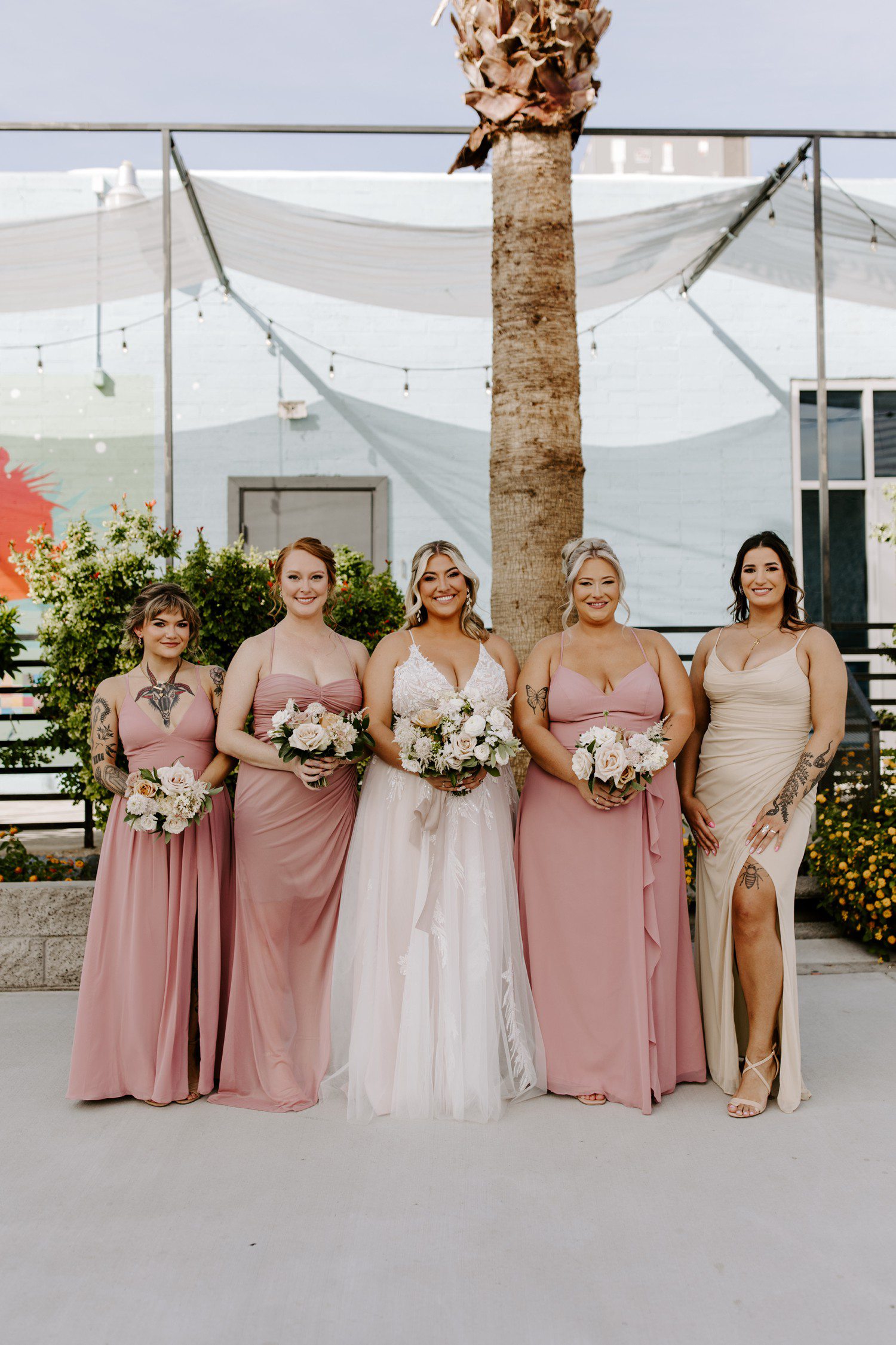 Bride and bridesmaids wearing mauve pink dresses with bouquets.