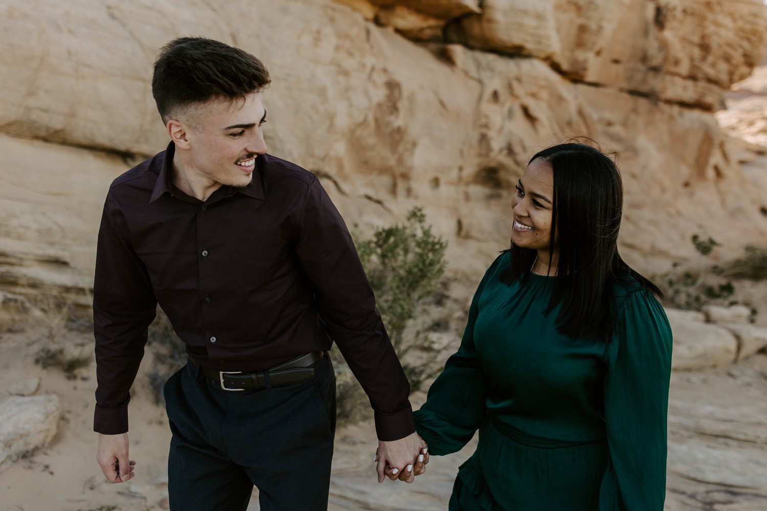 Couple holding hands and walking for engagement photos at Valley of Fire.