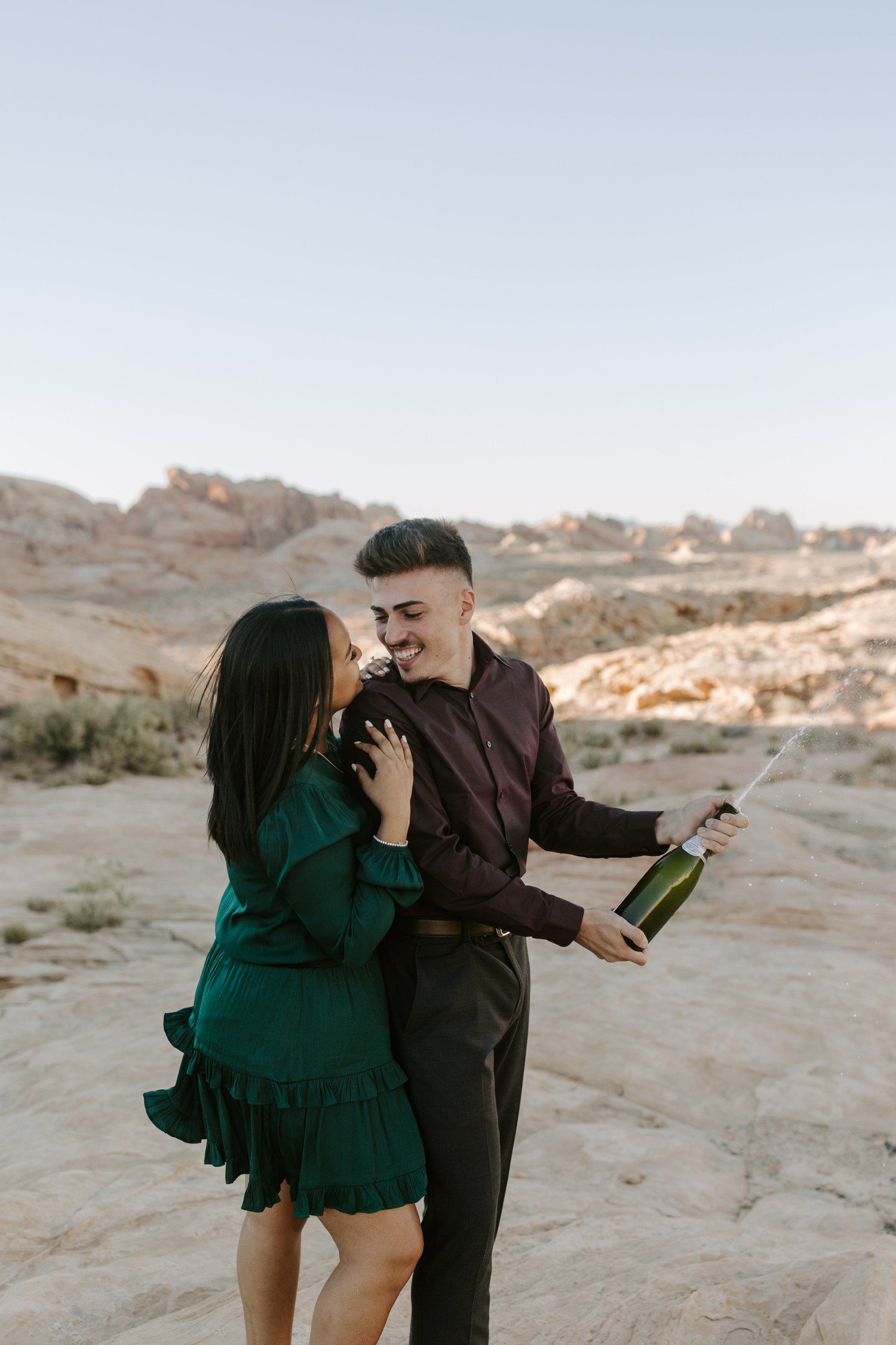 Couple popping champagne to celebrate proposal outside of Las Vegas.