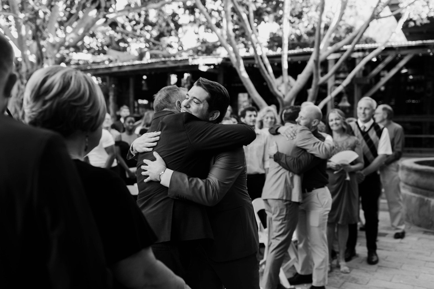 Groom hugging family after walking down aisle.