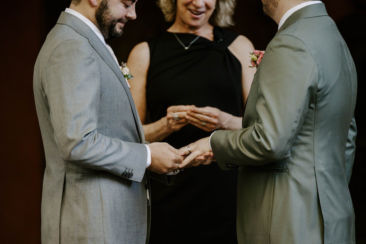 Grooms exchanging wedding rings during wedding ceremony.