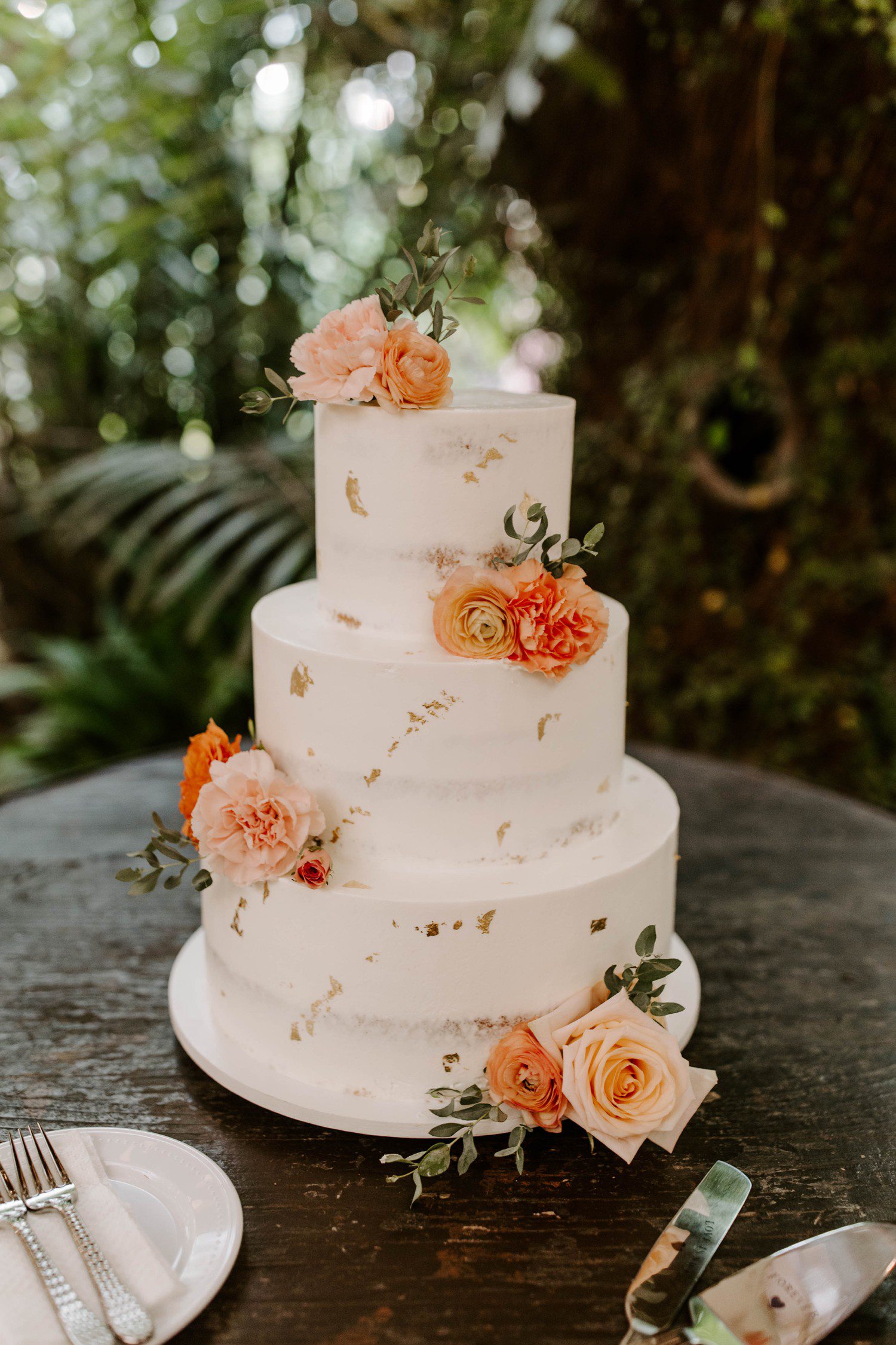 White and gold flecked wedding Cake with orange and pink flowers.
