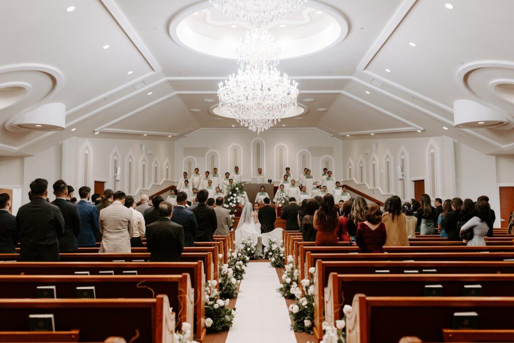 Wedding ceremony with white floral bouquets down aisle.