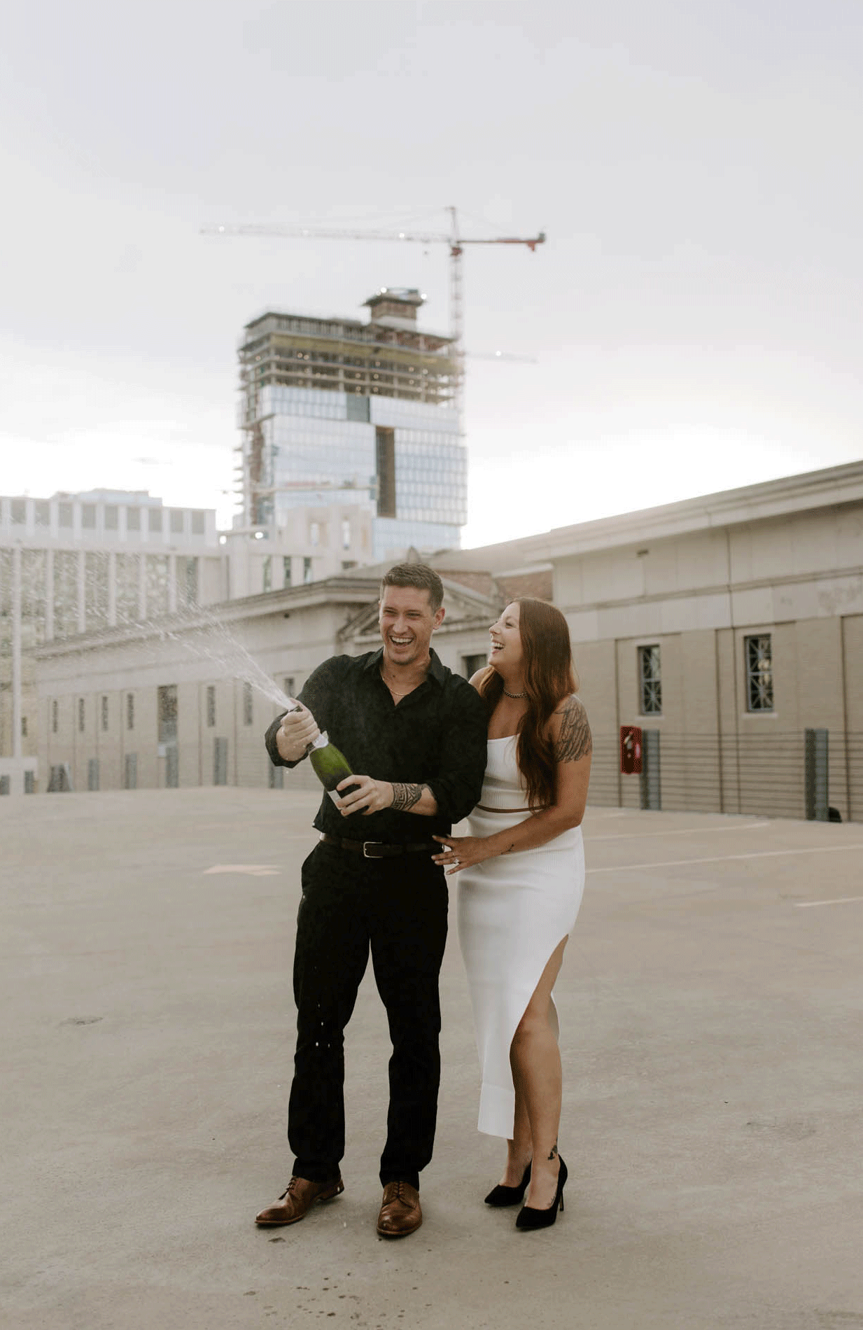 Couple popping champagne to celebrate being engaged. A guide on what to do after getting engaged. 
