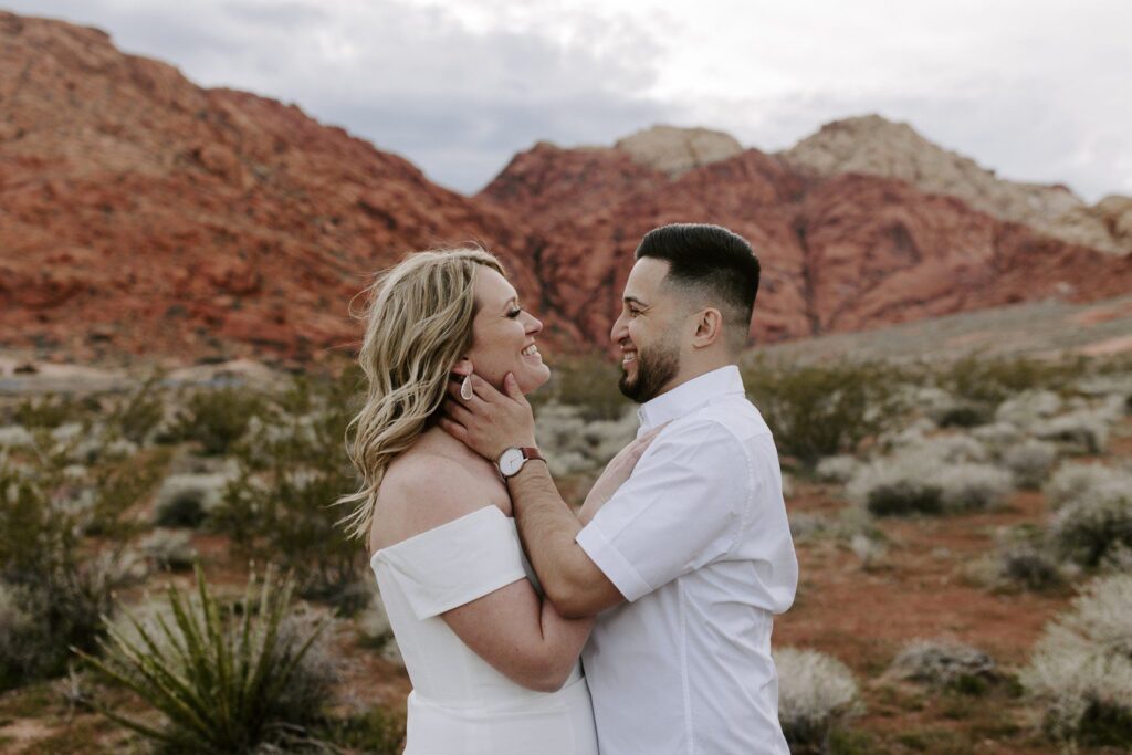 Red Rock Canyon engagement photos in Las Vegas with couple smiling at each other. 