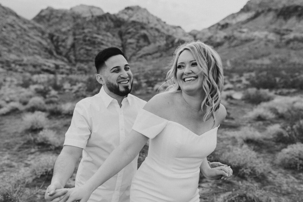 Couple smiling during engagement photos at Red Rocks in Las Vegas. 