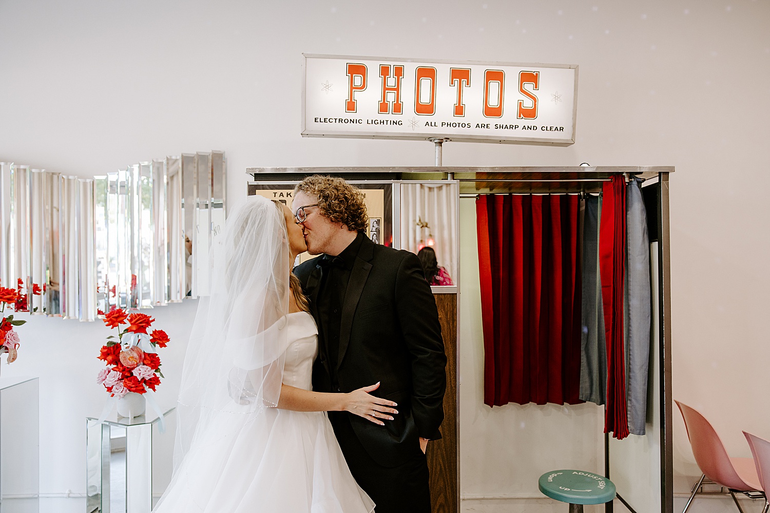 newlyweds share a kiss in front of photo booth at Sure Thing Chapel