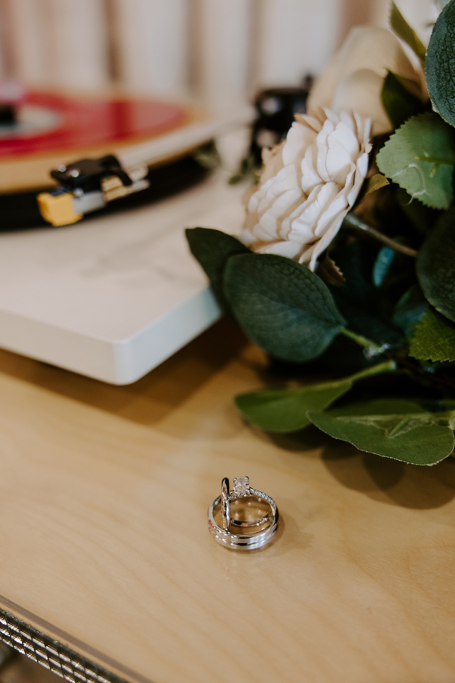 diamond rings on wooden table by bridal bouquet by Las Vegas elopement photographer