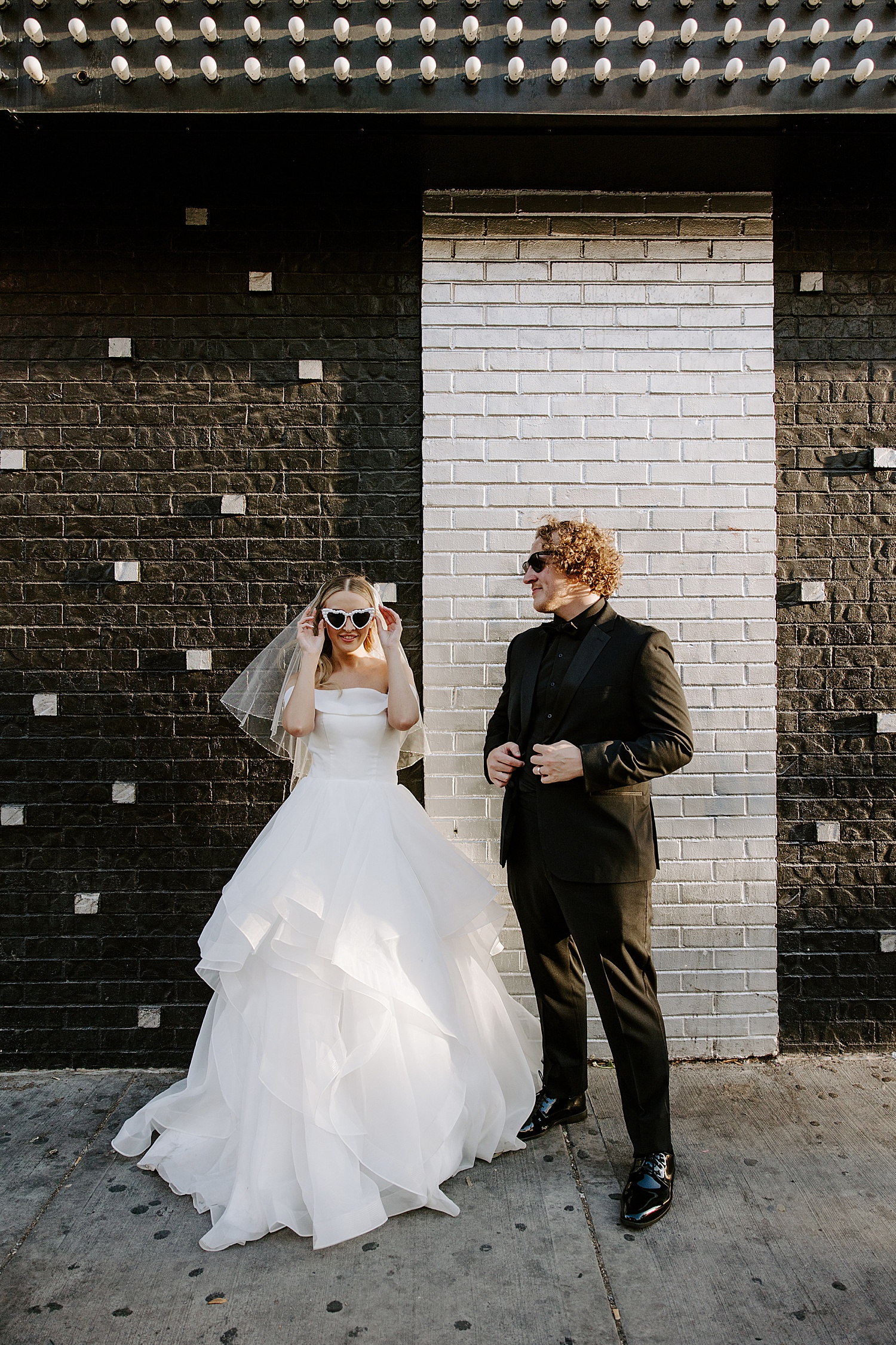 bride straightens white heart sunglasses by Katelyn Faye Photography