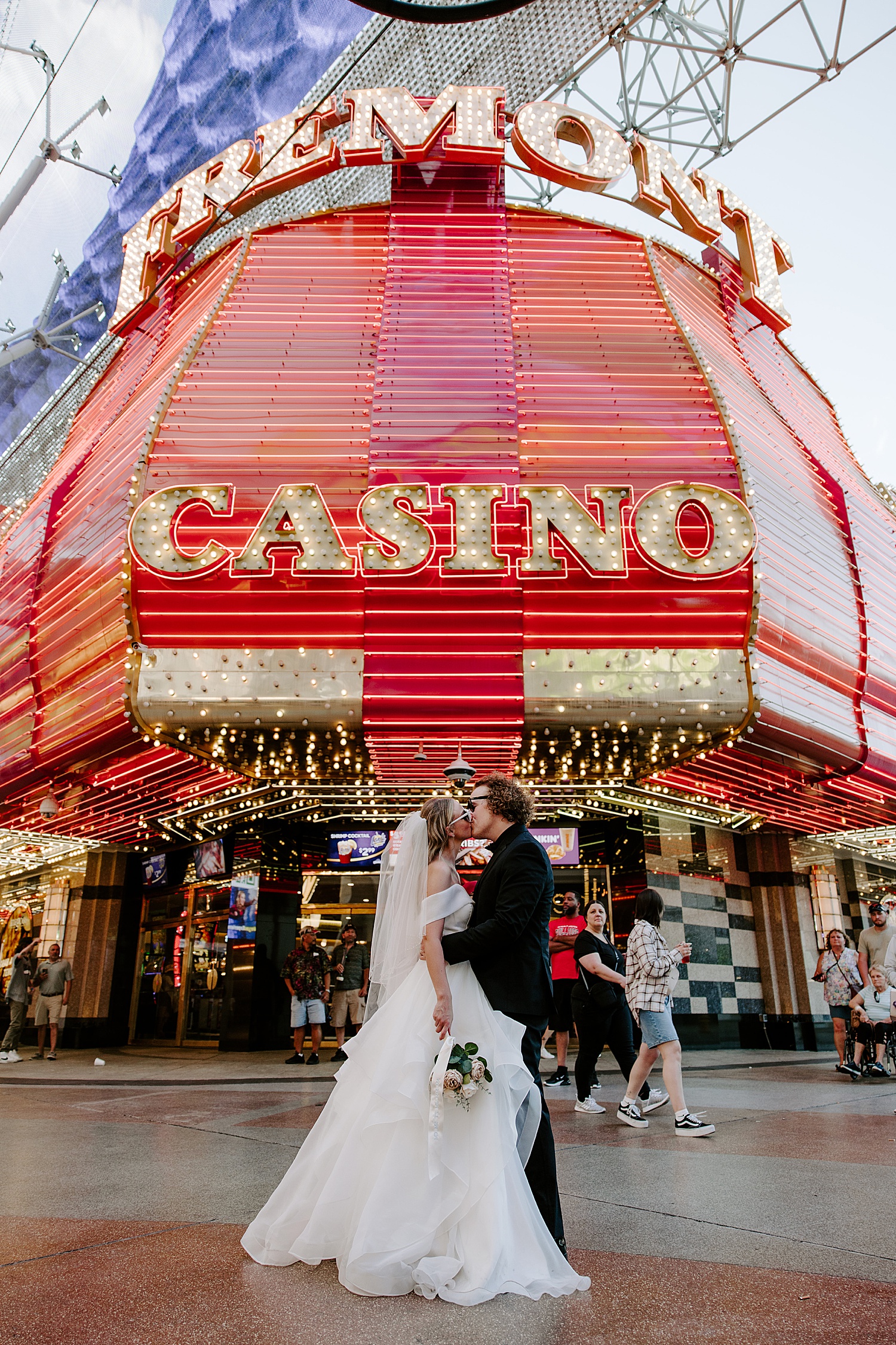 man holds his bride in front of large casino sign by Las Vegas elopement photographer