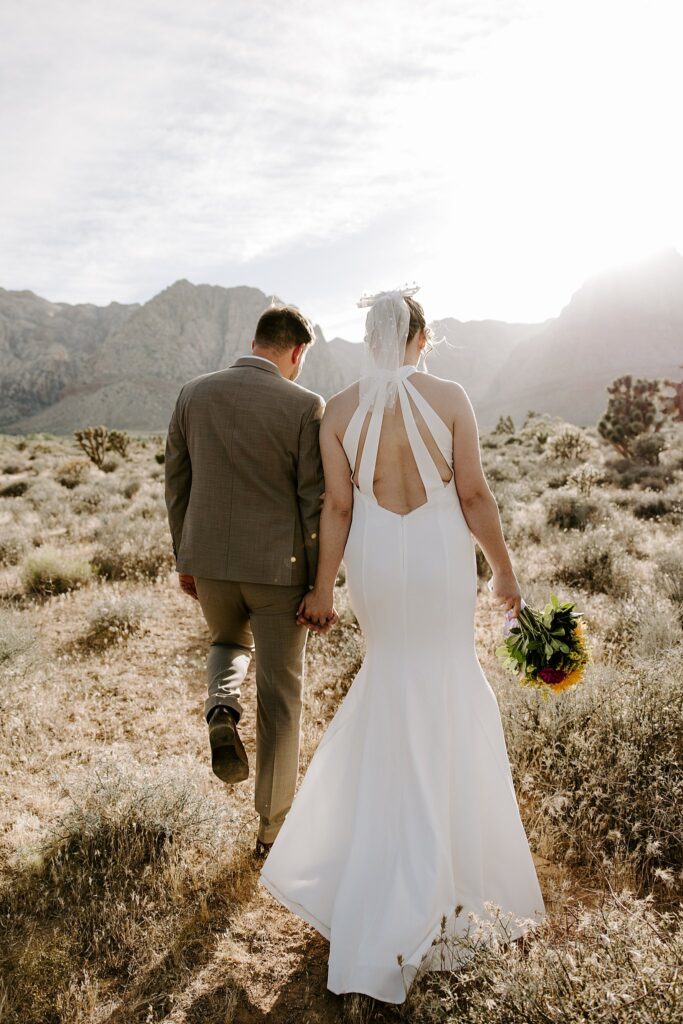 newlyweds walks hand in hand through the desert at Spring Mountains elopement