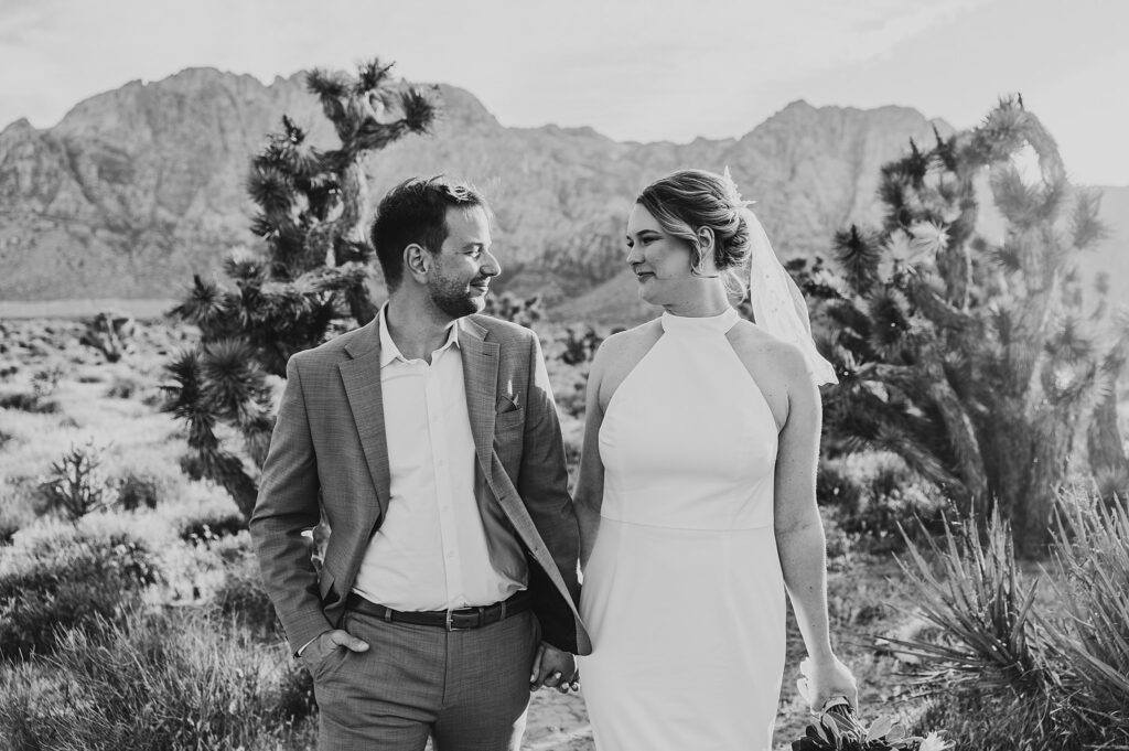 couple holds hands and looks at each other in desert by Katelyn Faye Photography