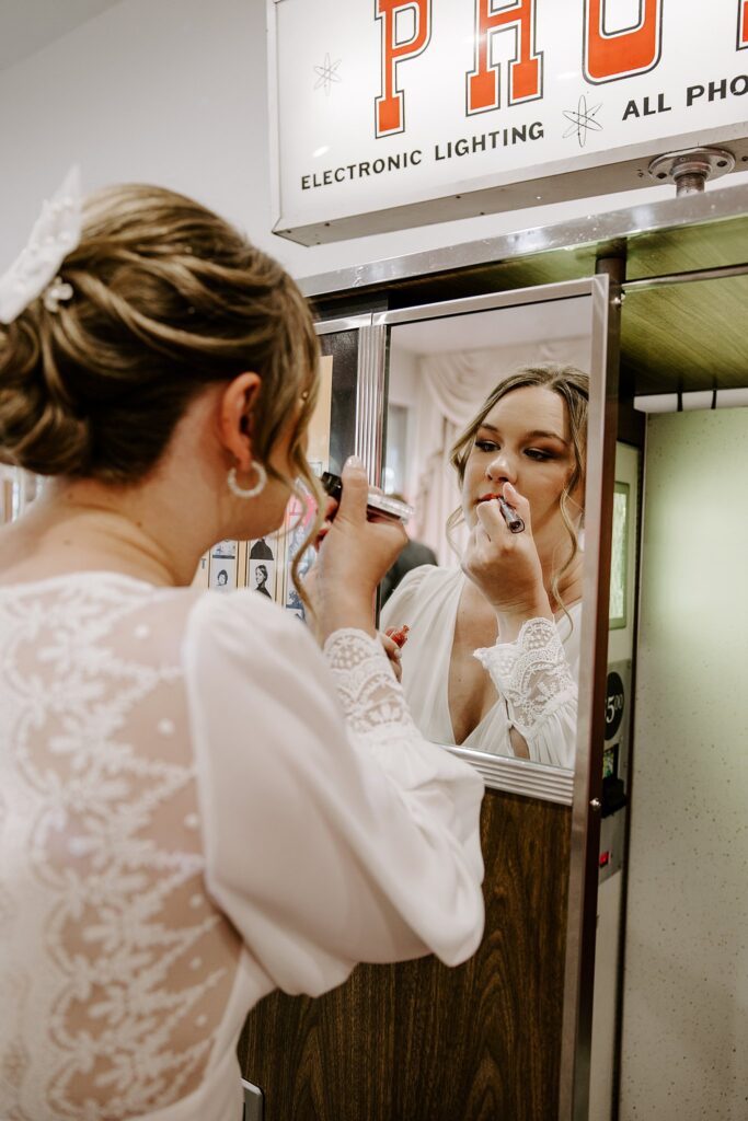 bride fixes her lipstick in photobooth mirror at Spring Mountains elopement