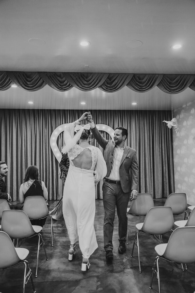 groom spins bride as they walk down aisle by Las Vegas wedding photographer