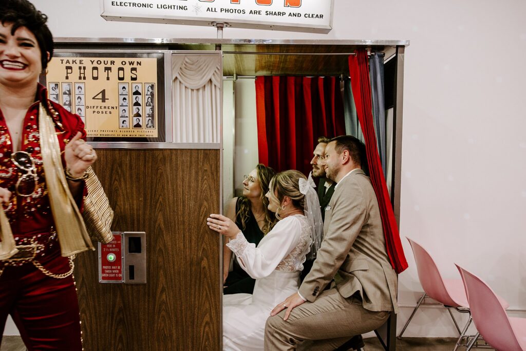 Elvis impersonator grins while newlyweds and guests crowd into photobooth by Katelyn Faye Photography