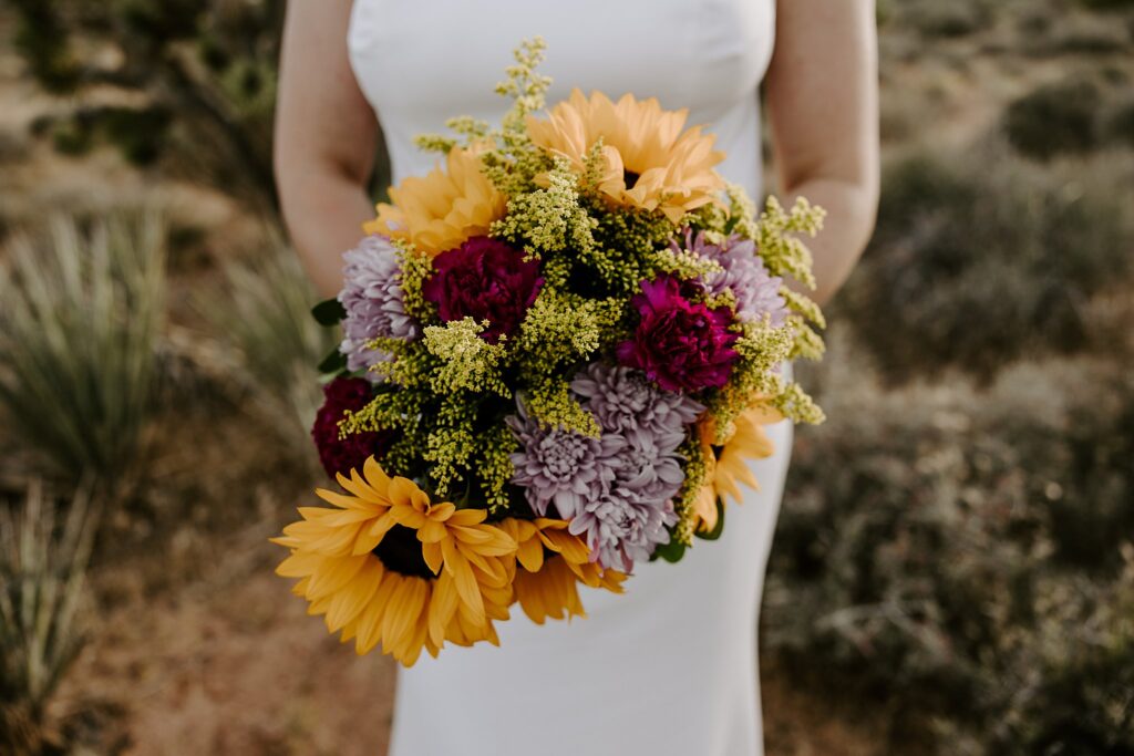 colorful sunflower and daisy florals held by bride by Las Vegas wedding photographer