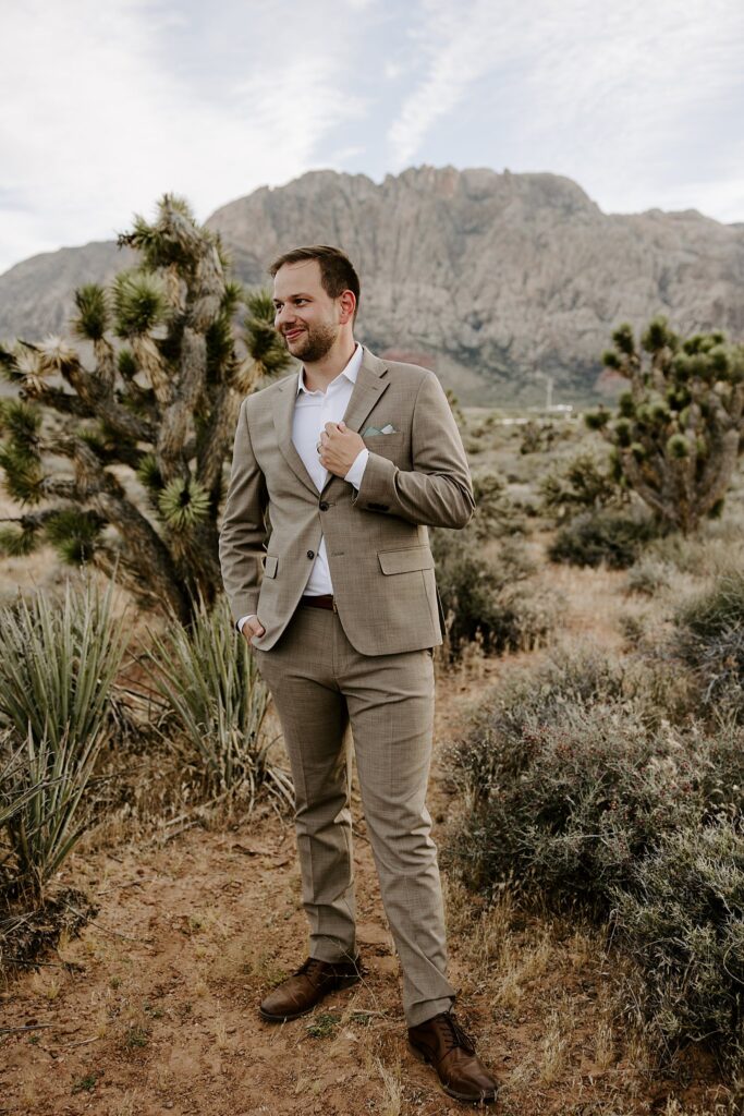 man holds lapel and has one hand in pocket during Spring Mountains elopement