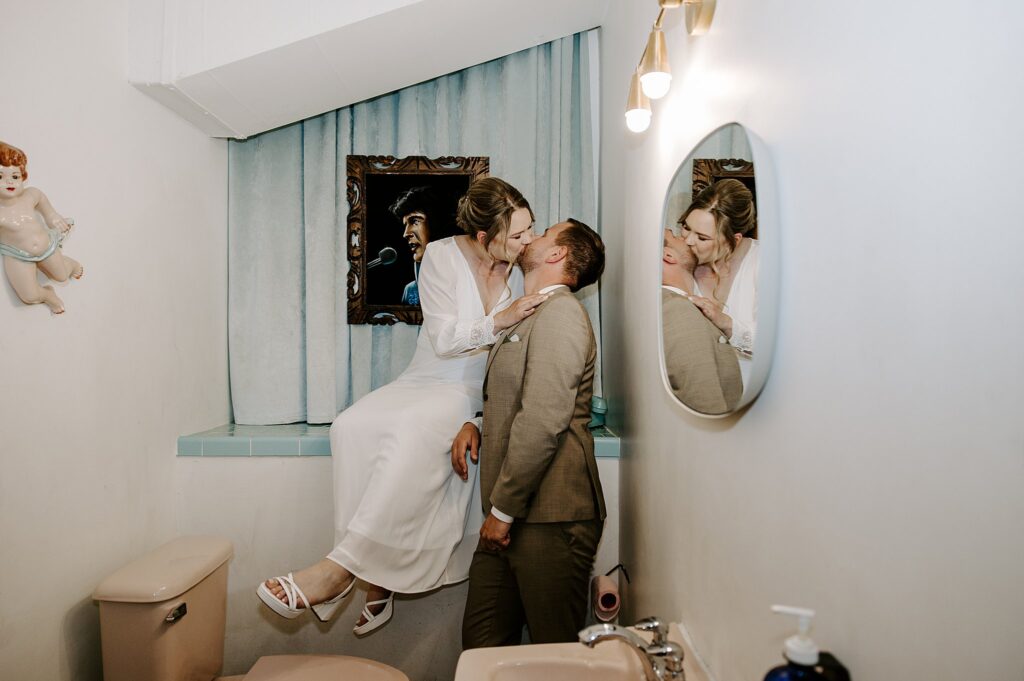 bride kisses groom in Elvis bathroom at Sure Thing Chapel by Katelyn Faye Photography