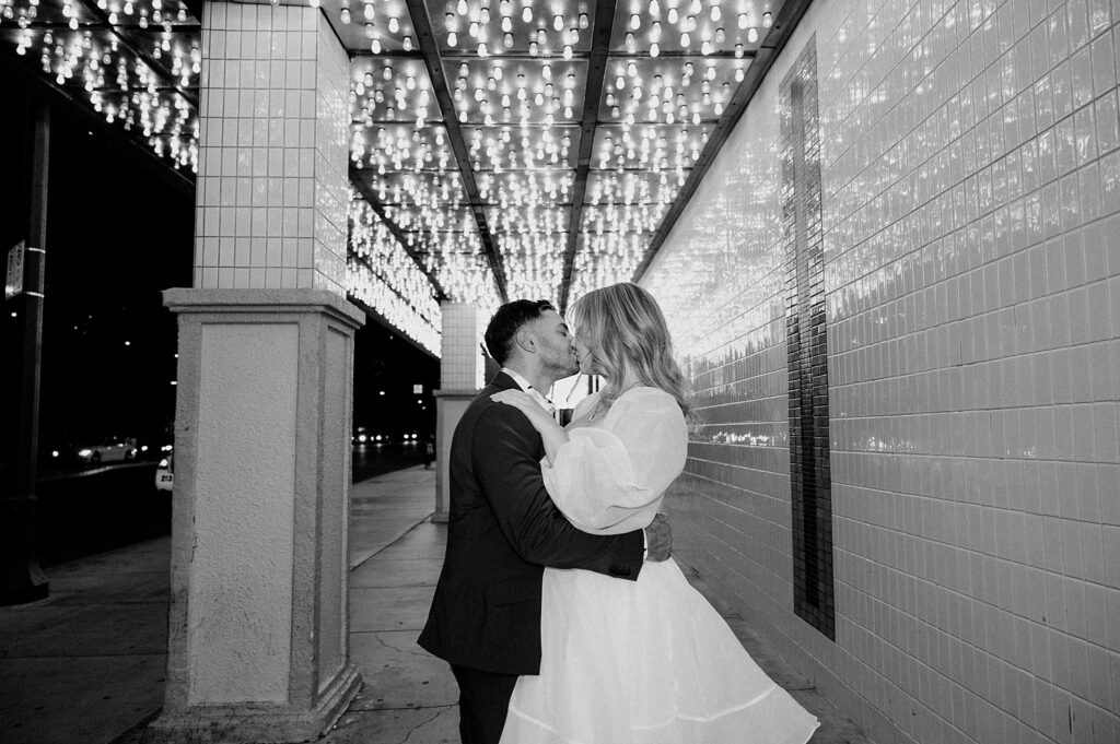 man and woman kiss under lights by Las Vegas elopement photographer