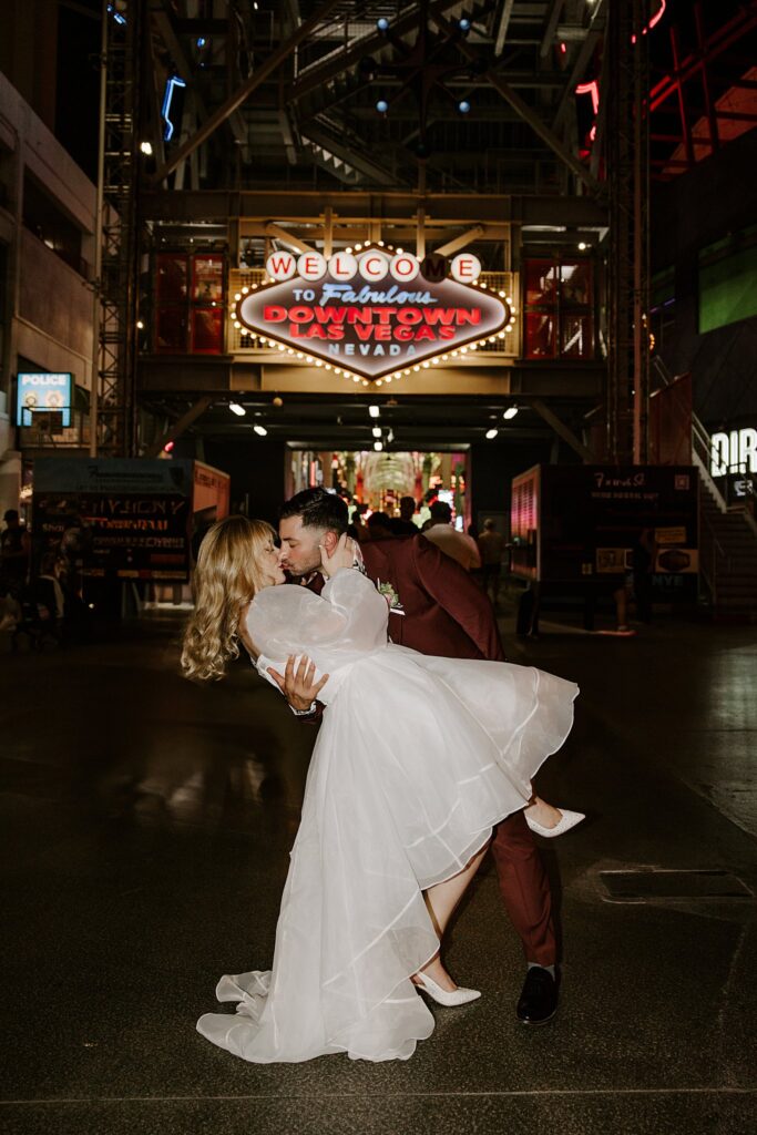 man dips his new wife on Fremont Street by Las Vegas elopement photographer