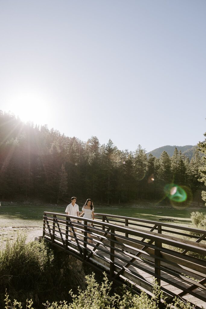 engaged couple walks across bridge by Las Vegas wedding photographer