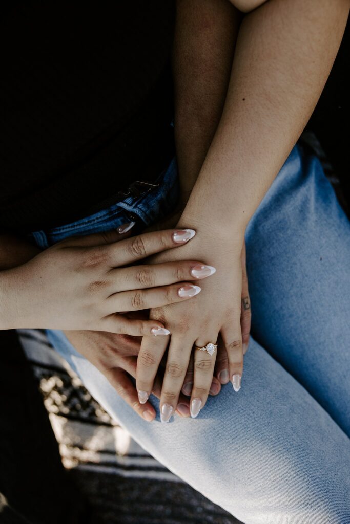 woman shows off ring with fiance's hands wrapped around her during Mt. Charleston engagement session 