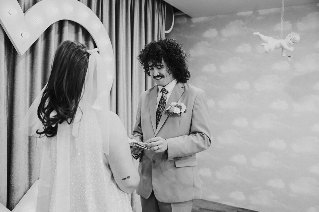 man smiles as he reads vows during elopement at Sure Thing Chapel