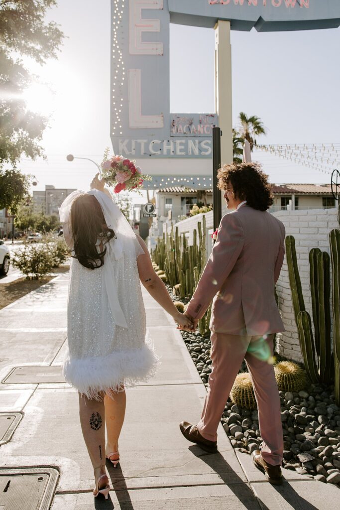 newlyweds walk down street holding hands after elopement at Sure Thing Chapel