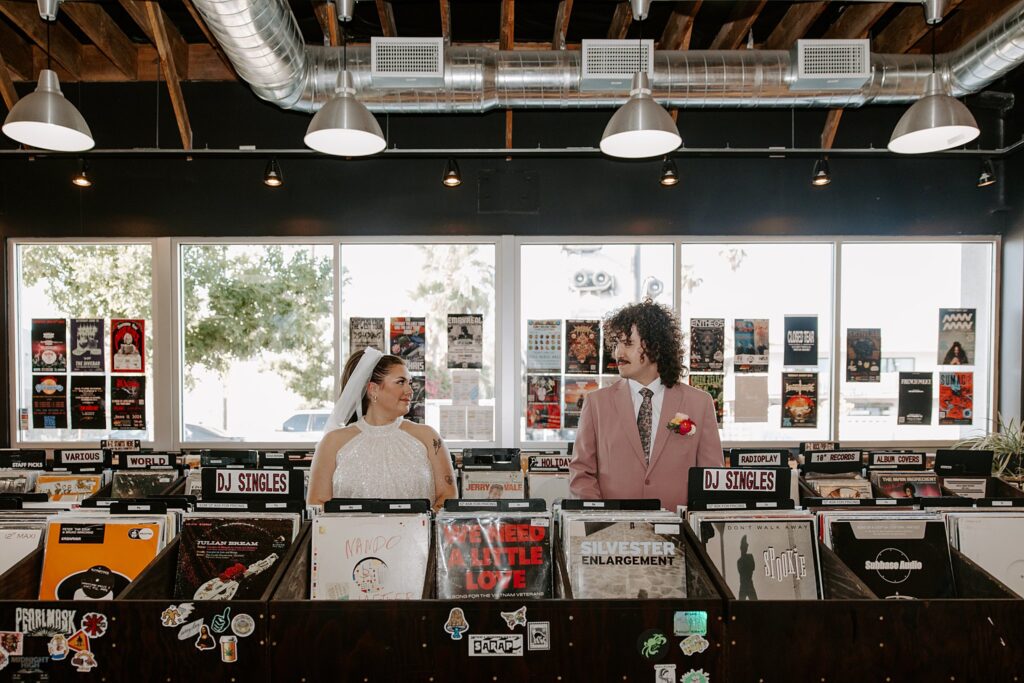 bride and groom look at each other in record shop by Vegas wedding photographer