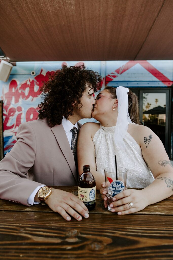 bride and groom kiss over drinks by Vegas wedding photographer