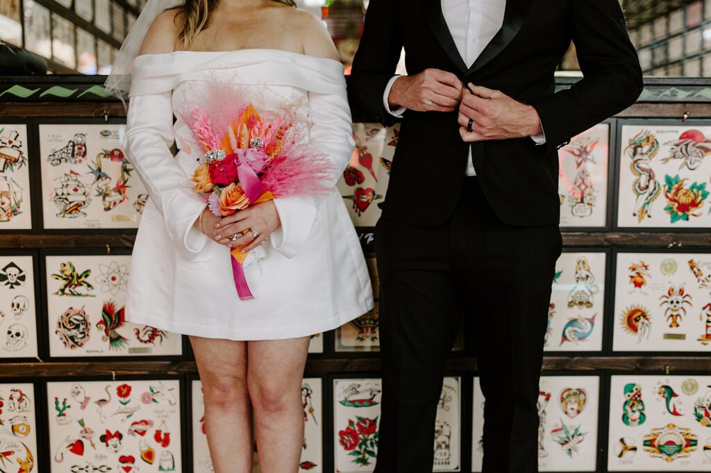 groom buttons coat and bride holds bouquet at Downtown Tattoo shop