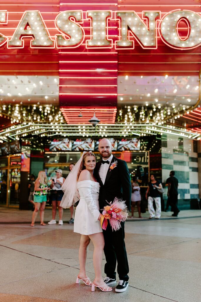 newlyweds smile together under casino sign by Katelyn Faye Photography