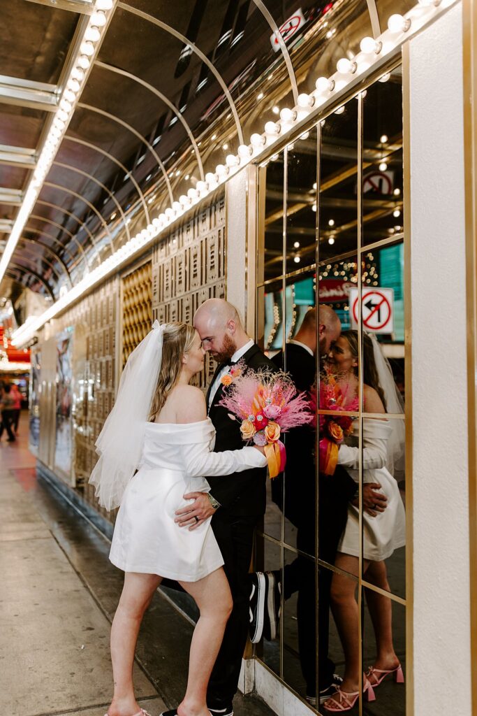 newlyweds lean against mirrored wall by Katelyn Faye Photography