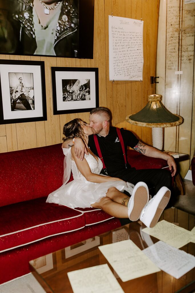 newlyweds sit on couch and kiss by Katelyn Faye Photography 