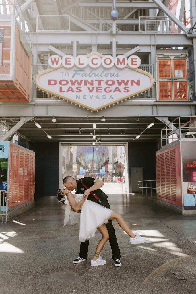 man dips bride in front of iconic sign after ceremony at the Punk Rock Museum