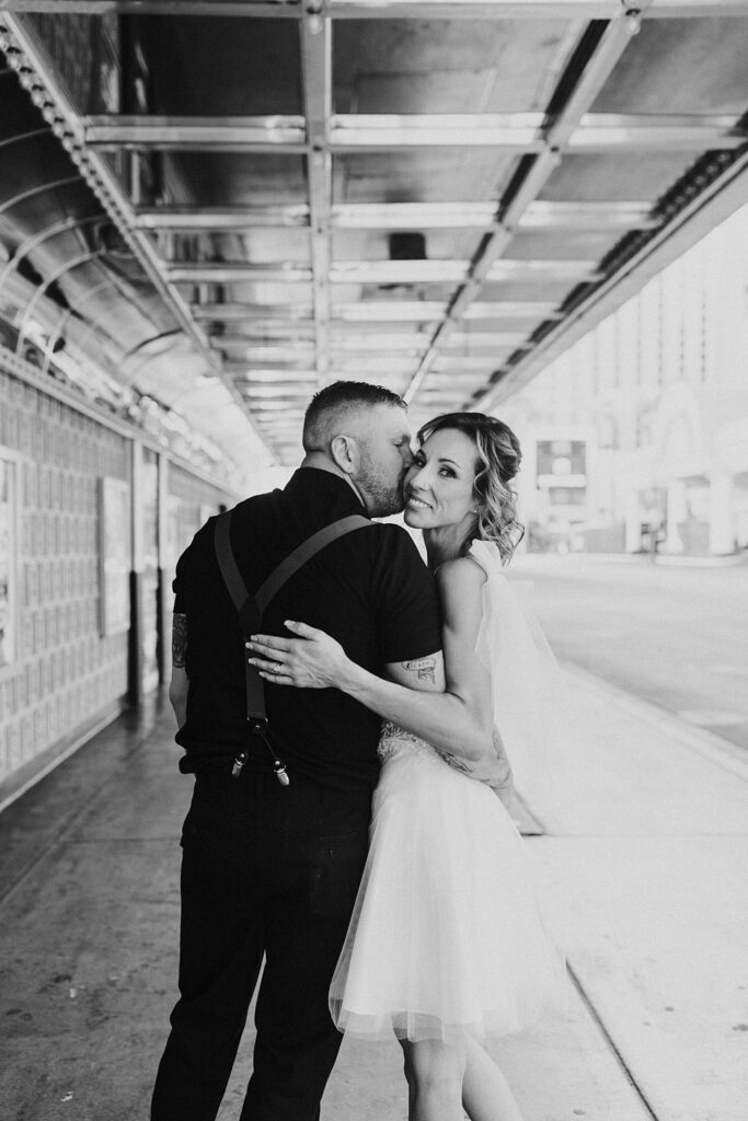 bride looks over her shoulder as man kisses her cheek by Katelyn Faye Photography 