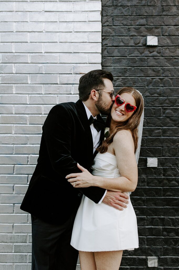 man kisses woman in red heart glasses by Las Vegas elopement photographer