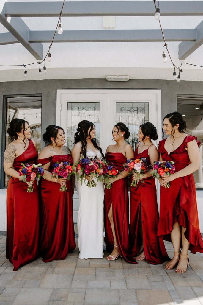 bridesmaids look at bride while holding bouquets by Las Vegas wedding photographer