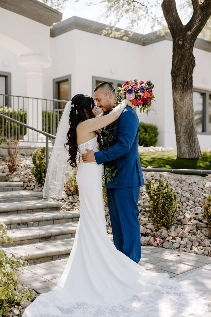 woman wraps arms around man's neck as they smile at each other at colorful ceremony at Adorn