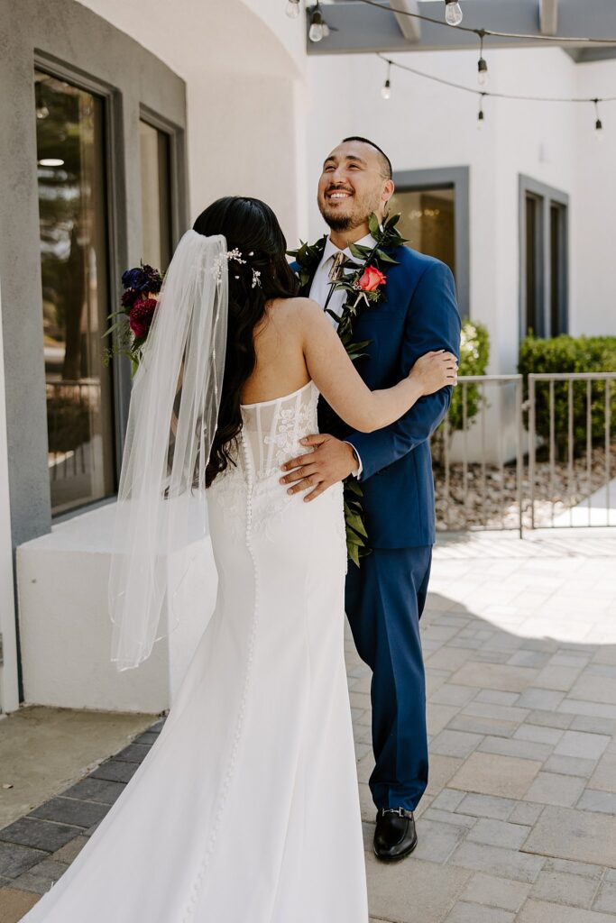 man holds woman's waist while he throws head back to smile and laugh by Las Vegas wedding photographer