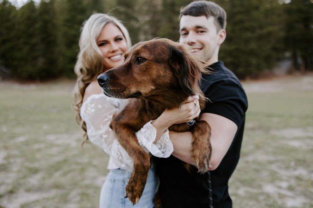 man and woman hold up dog at Fremont Street engagement session 