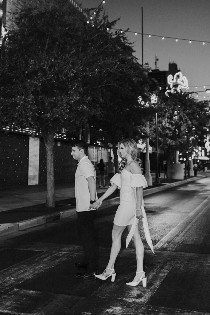 man and woman cross street hand in hand at Fremont Street engagement session 