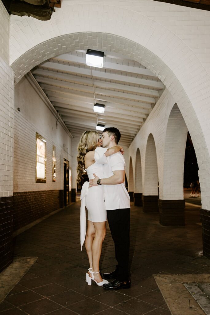 man and woman kiss in archway at Fremont Street engagement session 