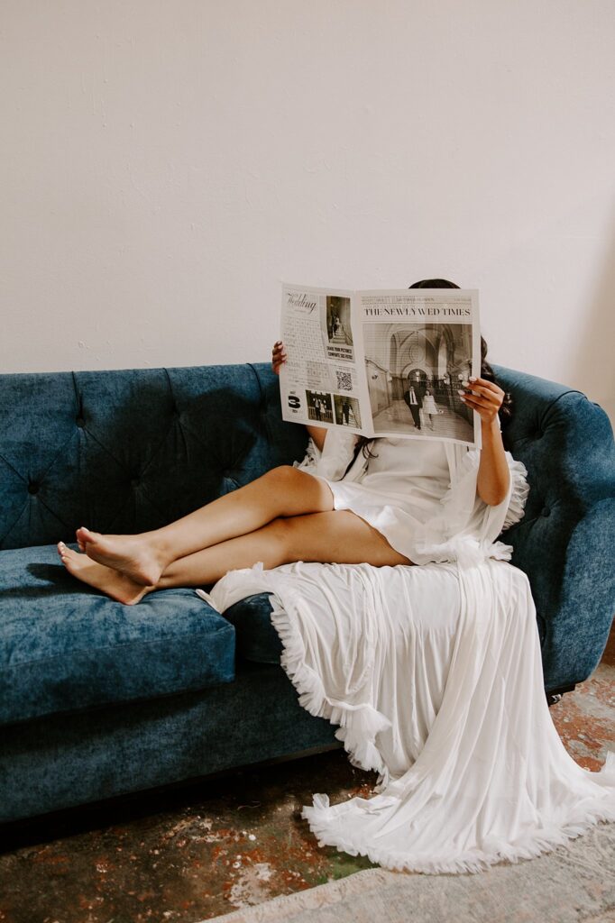 woman sits on blue couch at The Doyle reading a wedding program