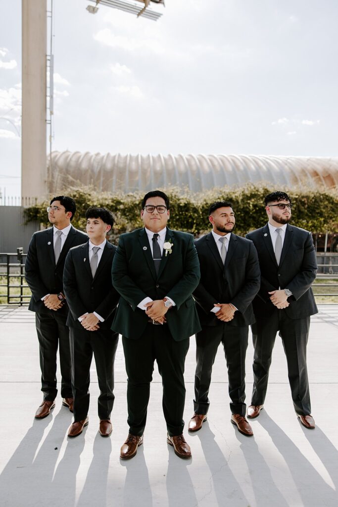 groomsmen stand together with hands crossed by Las Vegas Wedding Photographer