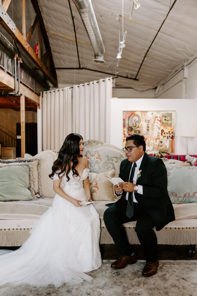 groom reads his personal vows to bride on couch by Las Vegas Wedding Photographer